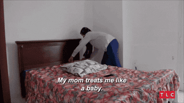 Person making a bed with text overlay "My mom treats me like a baby."