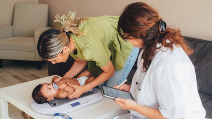Two healthcare professionals attending to a baby on an examination table