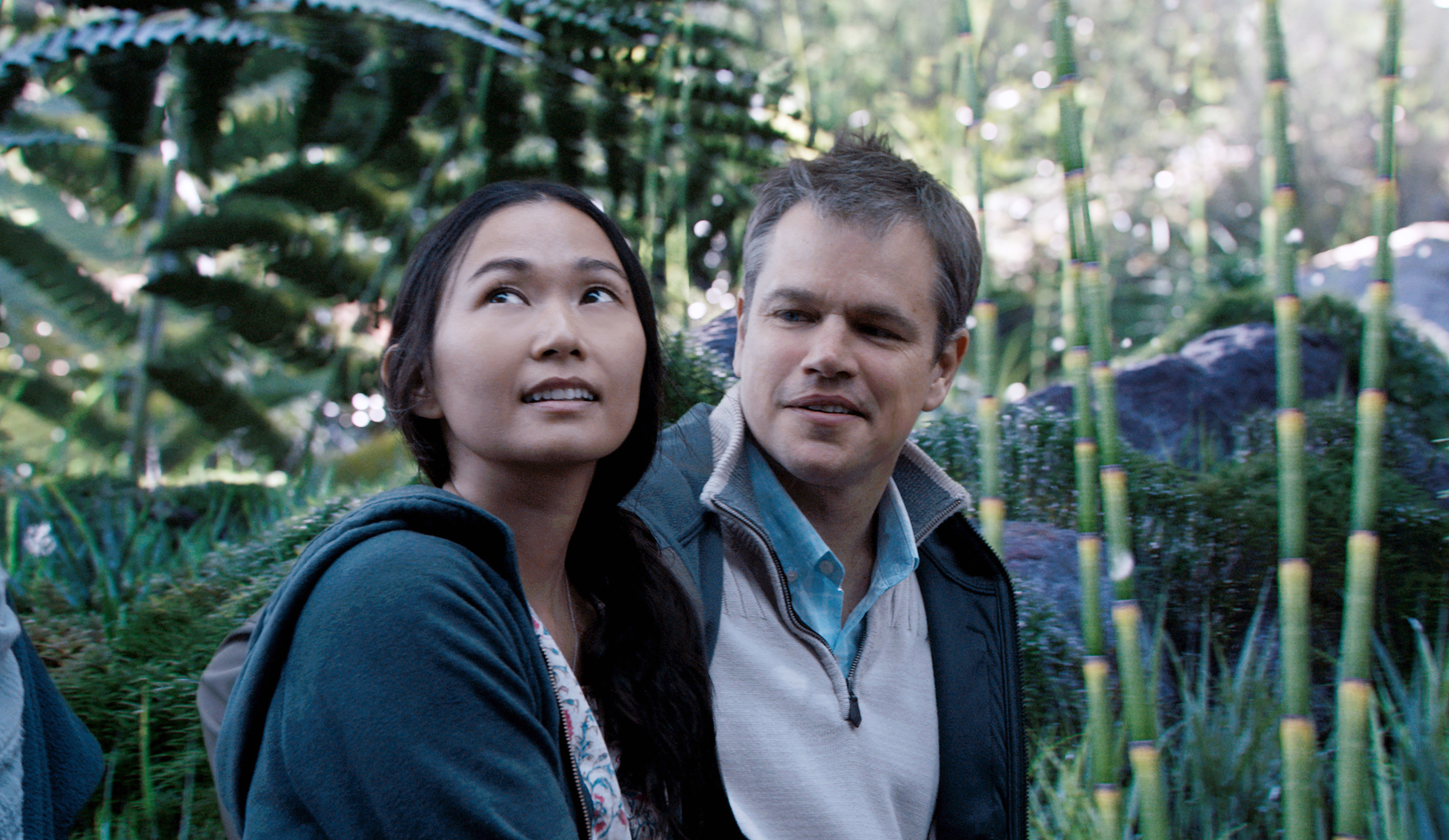 Two people gazing upward with curious expressions, standing outdoors