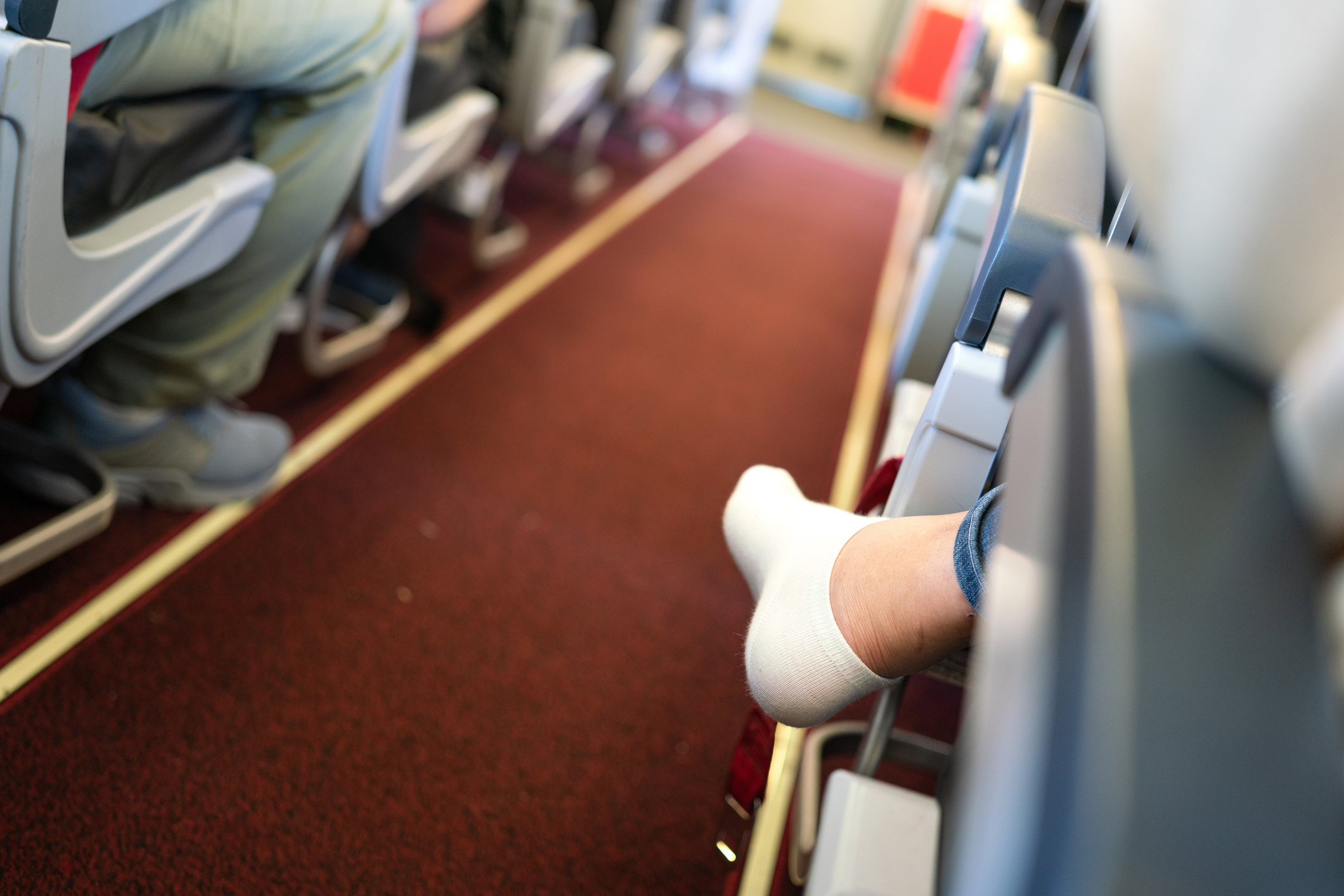 Passenger with feet up on airplane seats showcasing inconsiderate travel behavior