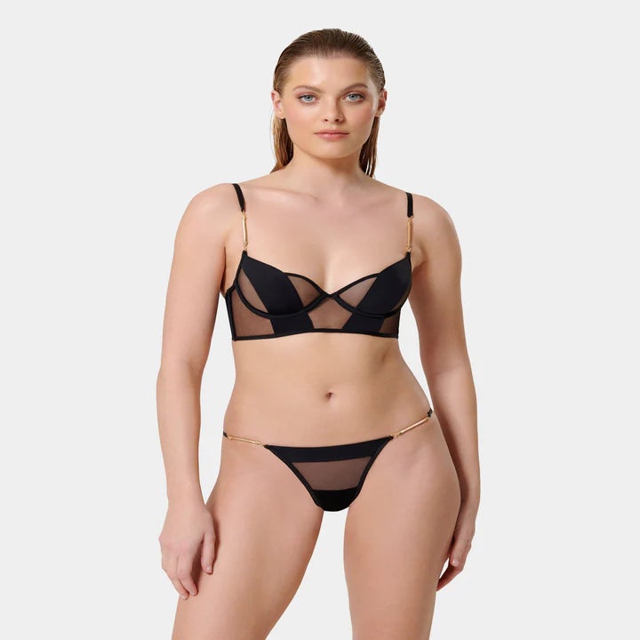 model wearing a black, sheer-paneled bra and underwear set
