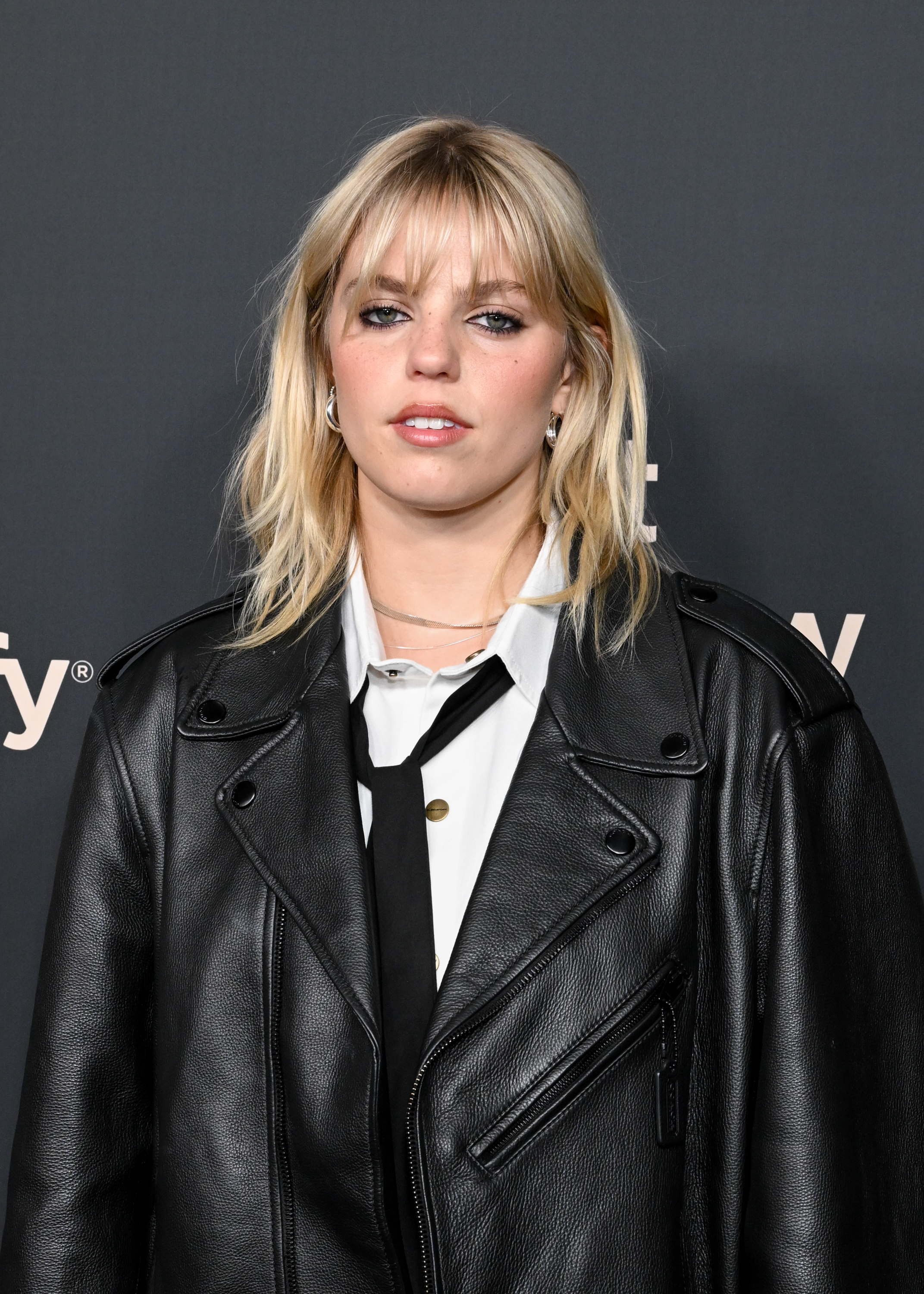 Reneé in a black leather jacket over a white top, attending an event