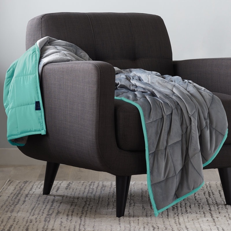 Weighted blanket draped over a modern chair, highlighting its thick texture and trim