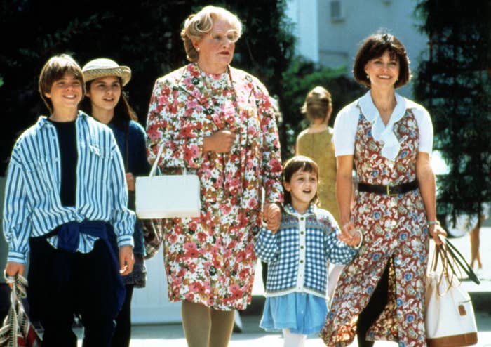 Group on a sunny day with actor in floral dress and white pearls, woman in patterned dress, boy in stripes, girl in plaid, and child in blue