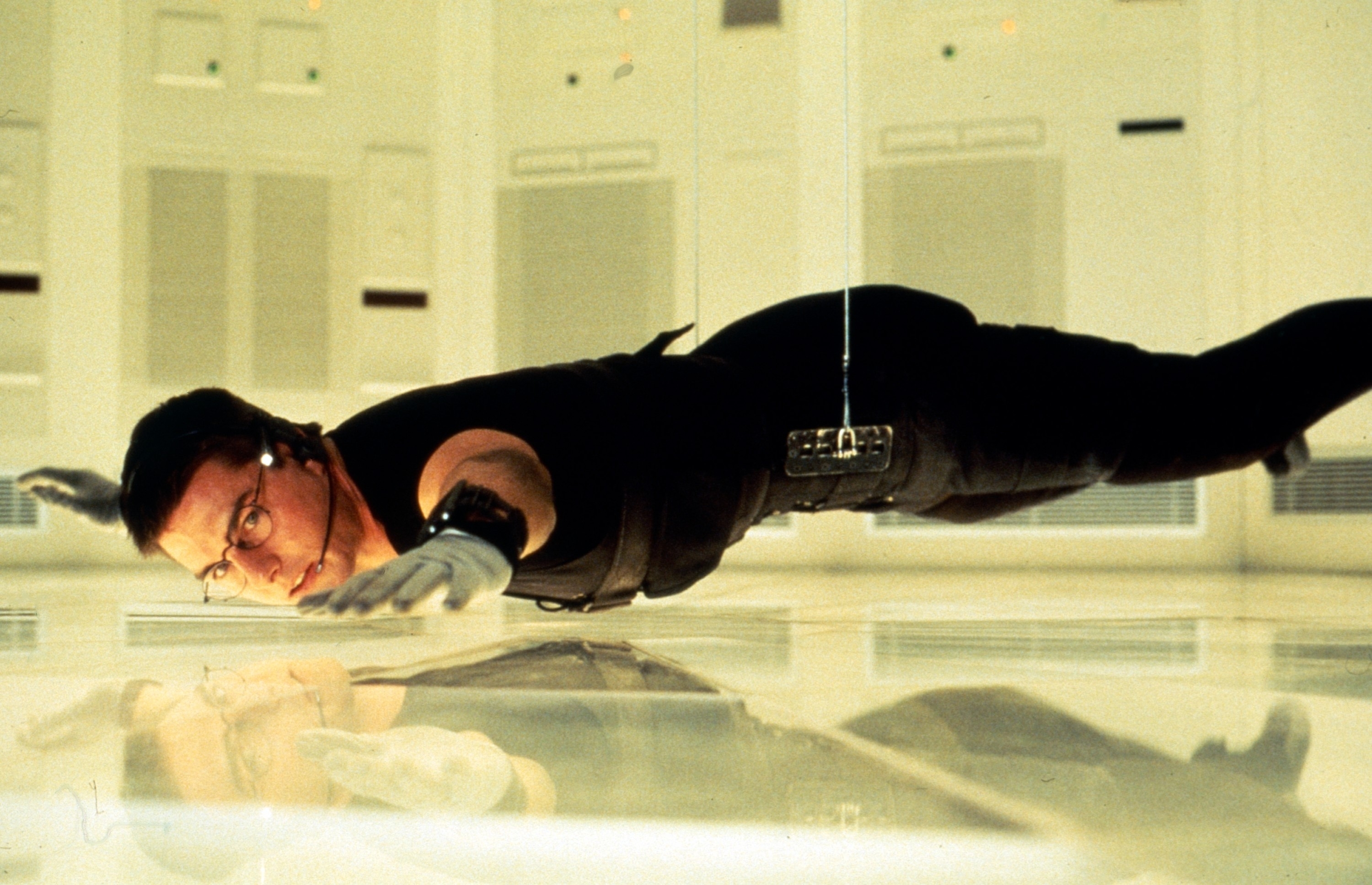 Ethan Hunt, a character from Mission: Impossible, is suspended mid-air during a heist scene