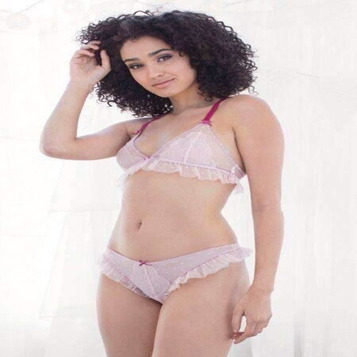 Woman in a lace-trimmed lingerie set posing against a light background