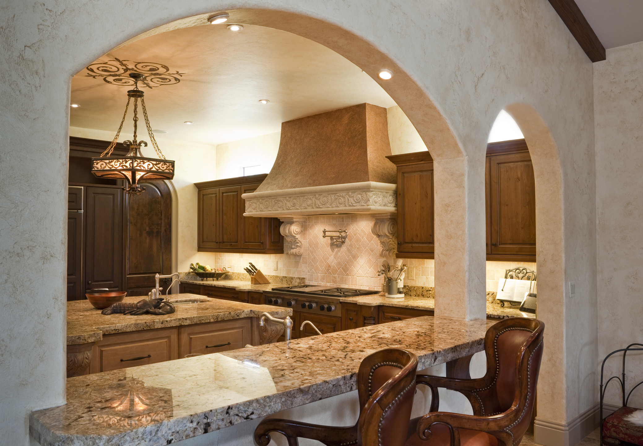Elegant kitchen with arched entryway, granite countertops, and detailed wooden cabinetry