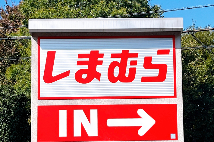 標識に「しまむら IN」と書かれた矢印が示す進行方向を案内しています。