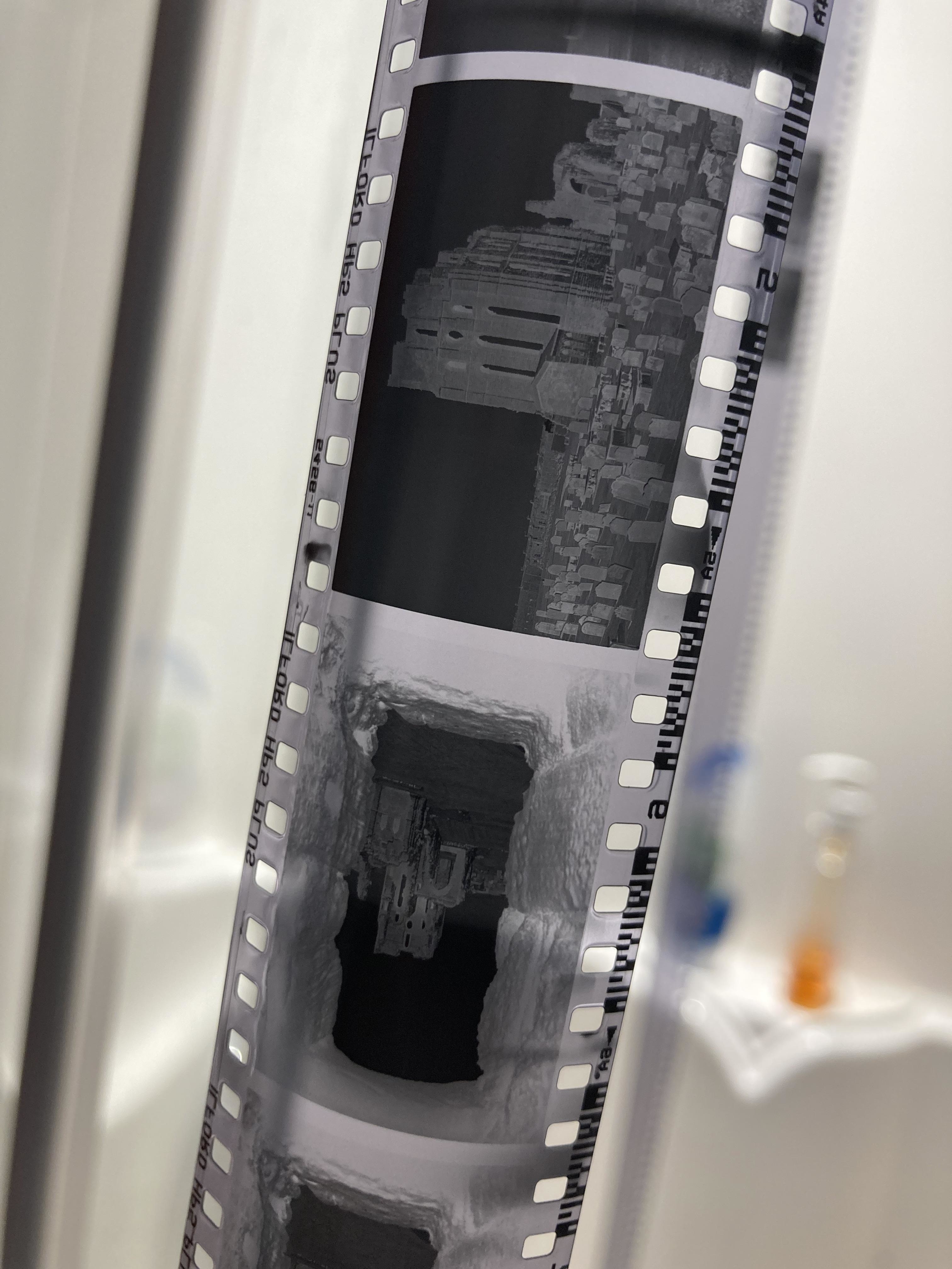 Two strips of film negatives showing pixelated images, likely from a video game, displayed in front of a blurred background
