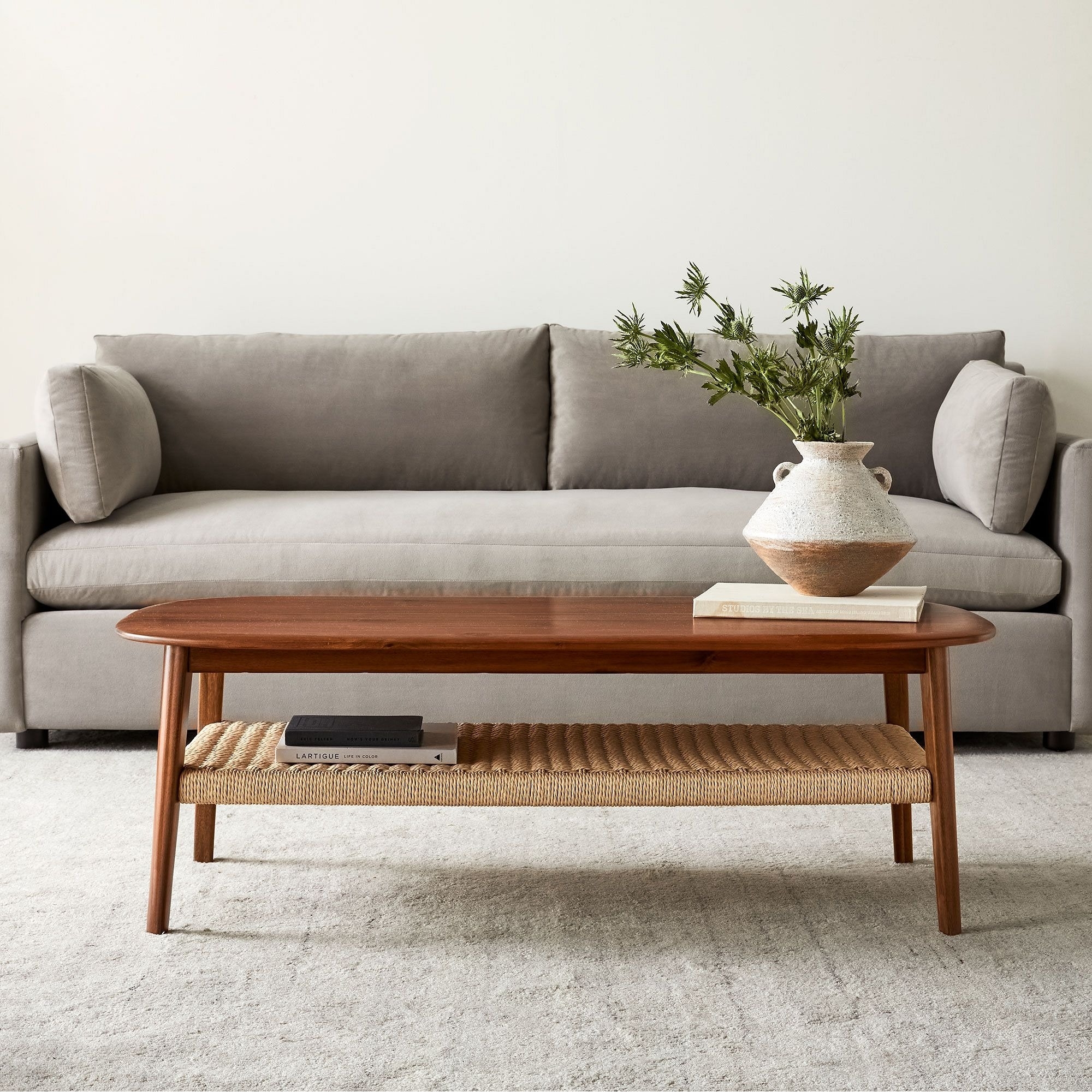 A neutral-toned sofa with a wooden coffee table displaying a vase, books, and a decorative tray in a living room