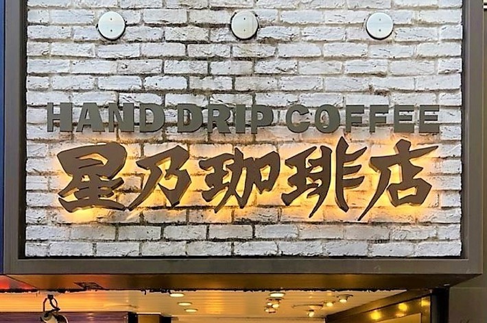 Sign with “HAND DRIP COFFEE” in English and Asian characters, mounted on a brick wall