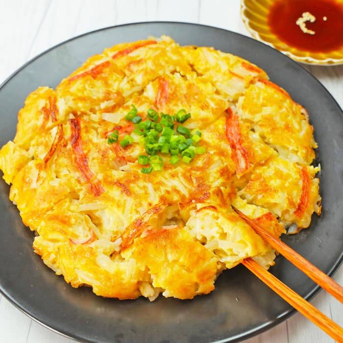 お皿に盛り付けられたチヂミ、薬味のネギが添えられています。