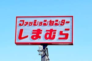 Billboard with Japanese text against a clear sky, mounted on a pole