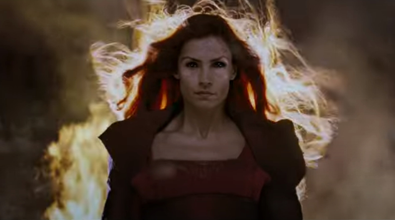 Woman with special effects flames behind her, intense expression, wearing a dark top