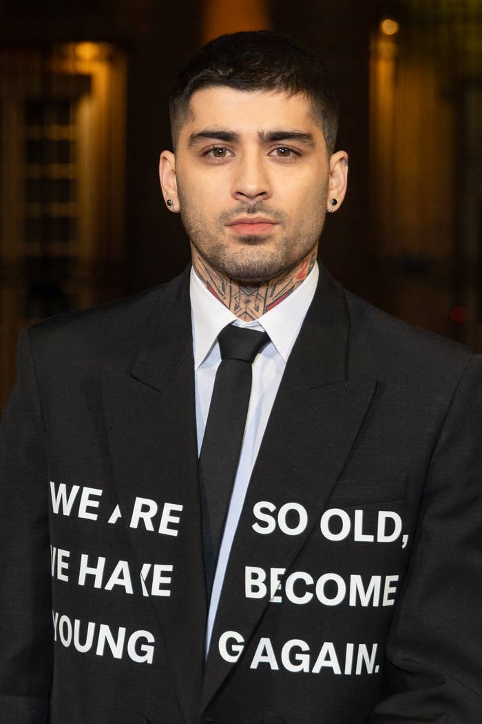 Zayn Malik in a black suit with text, looking at the camera