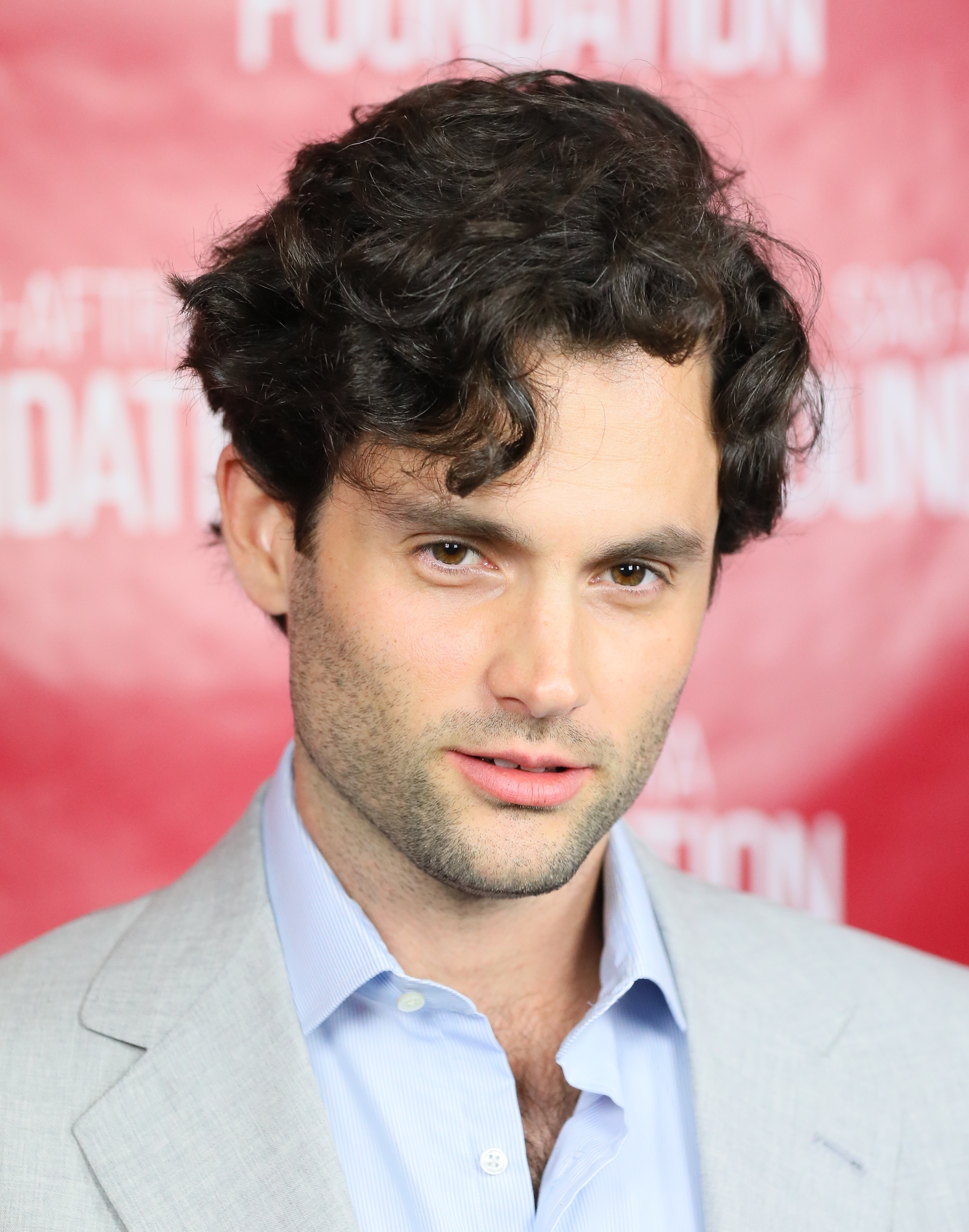 Penn Badgley in a blue shirt at an event, looking to the side