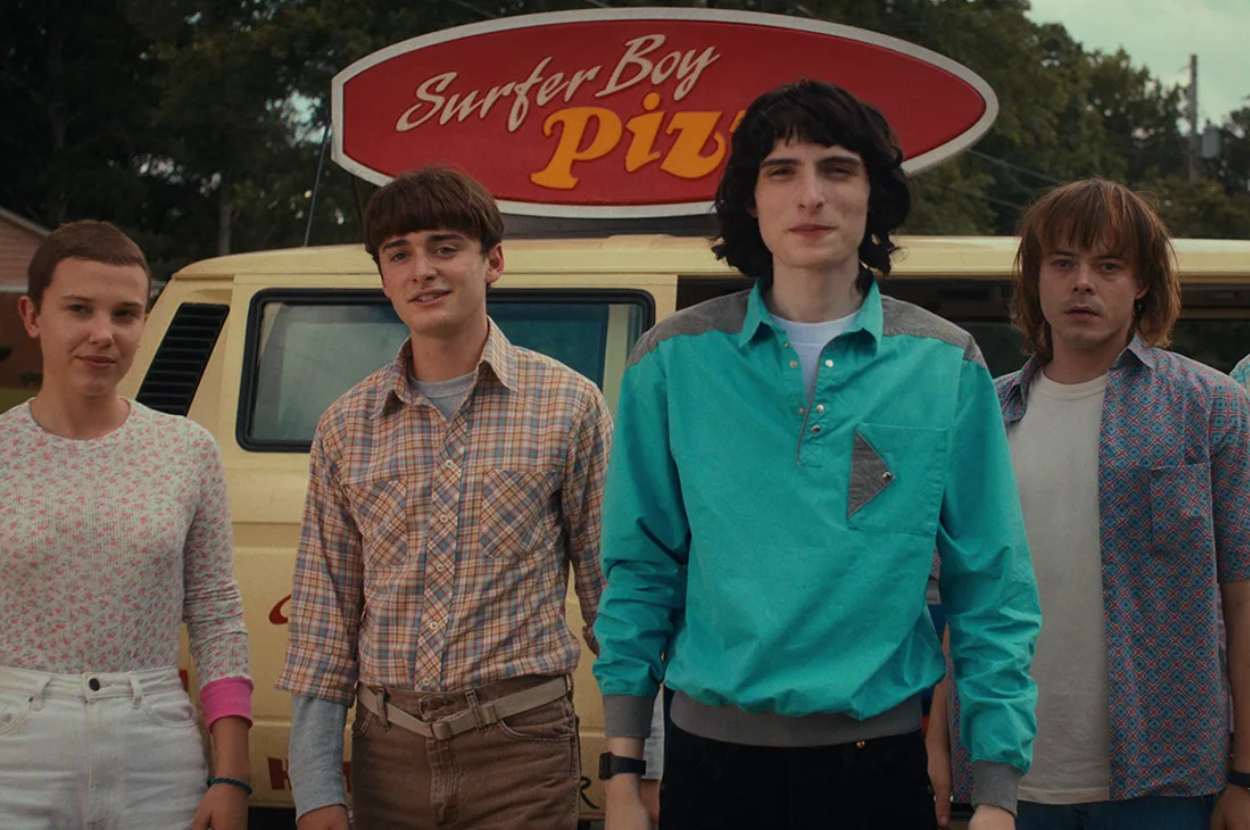Four actors from Stranger Things standing in front of Surfer Boy Pizza van