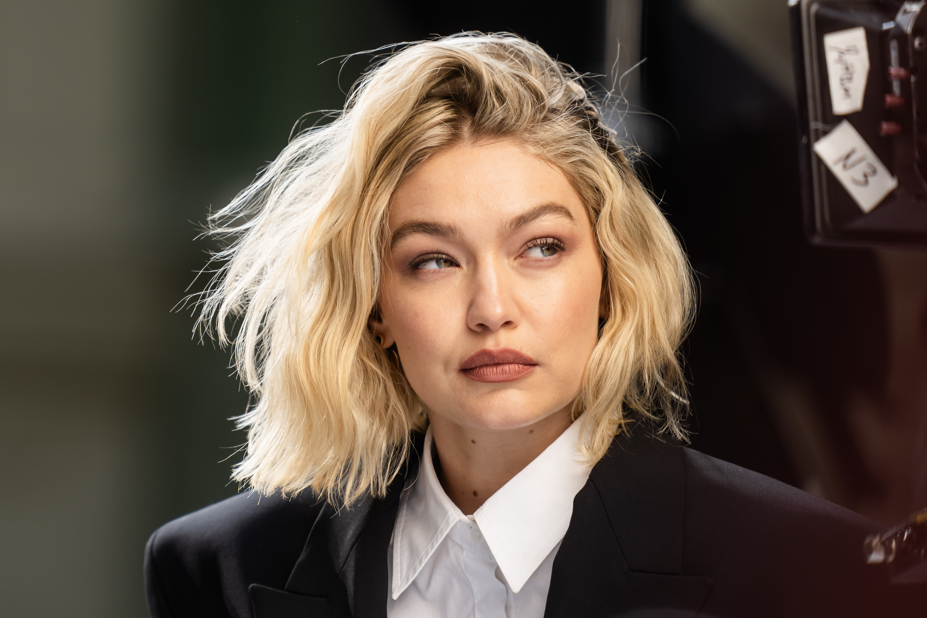 Gigi Hadid in a sleek suit looking away with a thoughtful expression