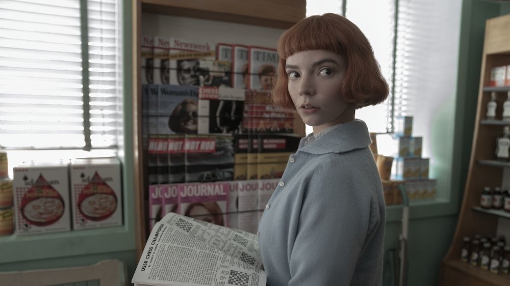 Character from &#x27;The Queen&#x27;s Gambit&#x27; standing in a pharmacy with vintage posters behind and holding a newspaper