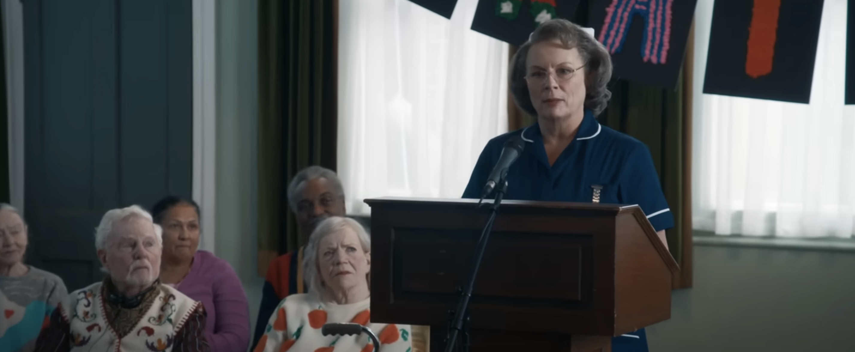 Sister Gilpin in nurse uniform speaking at a podium, audience in background