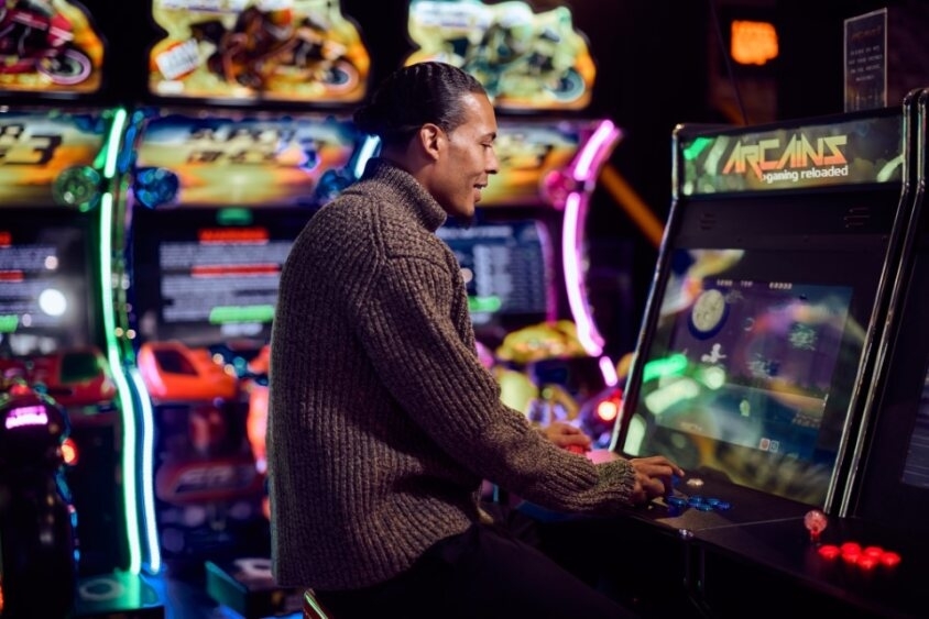 Man playing an arcade game in a gaming arcade, providing a recreational activity option for travelers