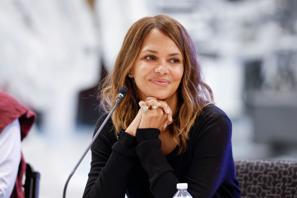 Woman sitting with hands clasped, smiling, at a discussion panel