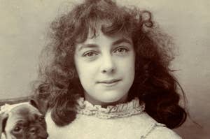 Vintage portrait of a young woman with curly hair and a small dog peeking over her shoulder