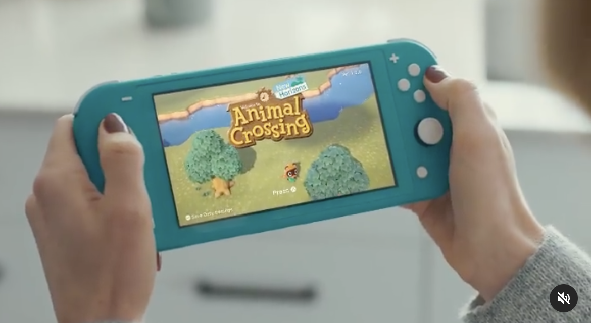 Person holding a game console with &#x27;Animal Crossing&#x27; on the screen