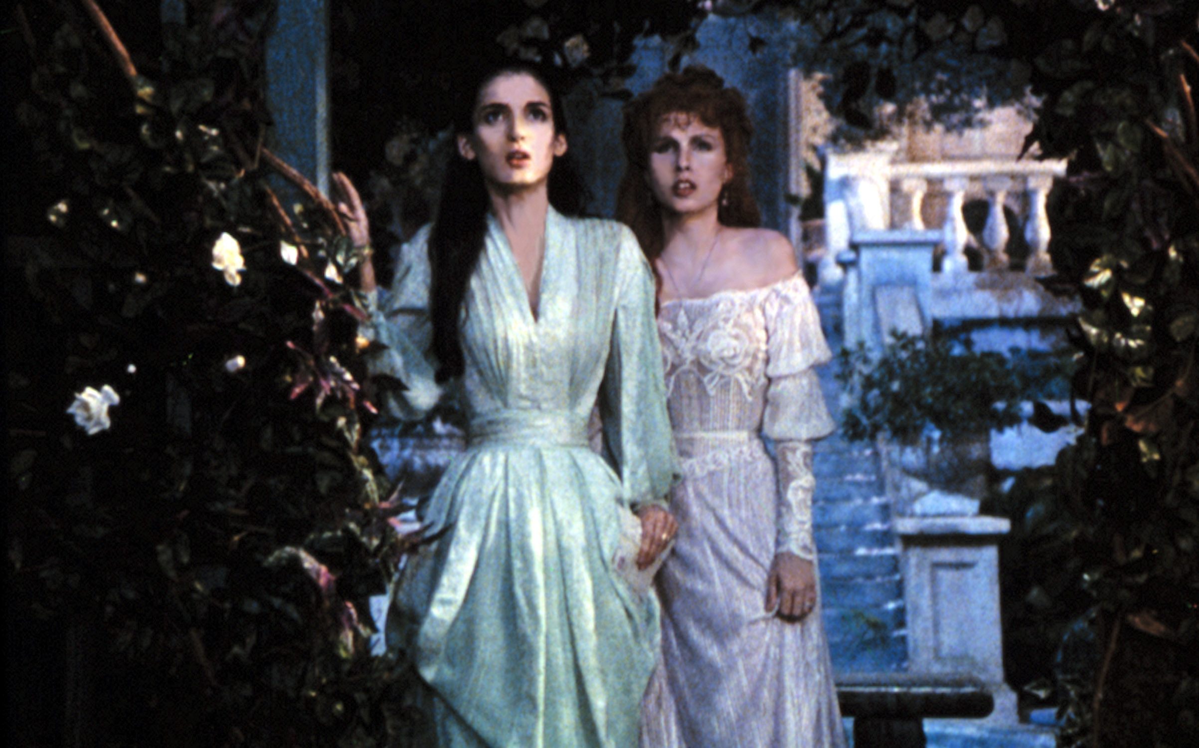 Two women in Victorian-style dresses look surprised in a scene from a film