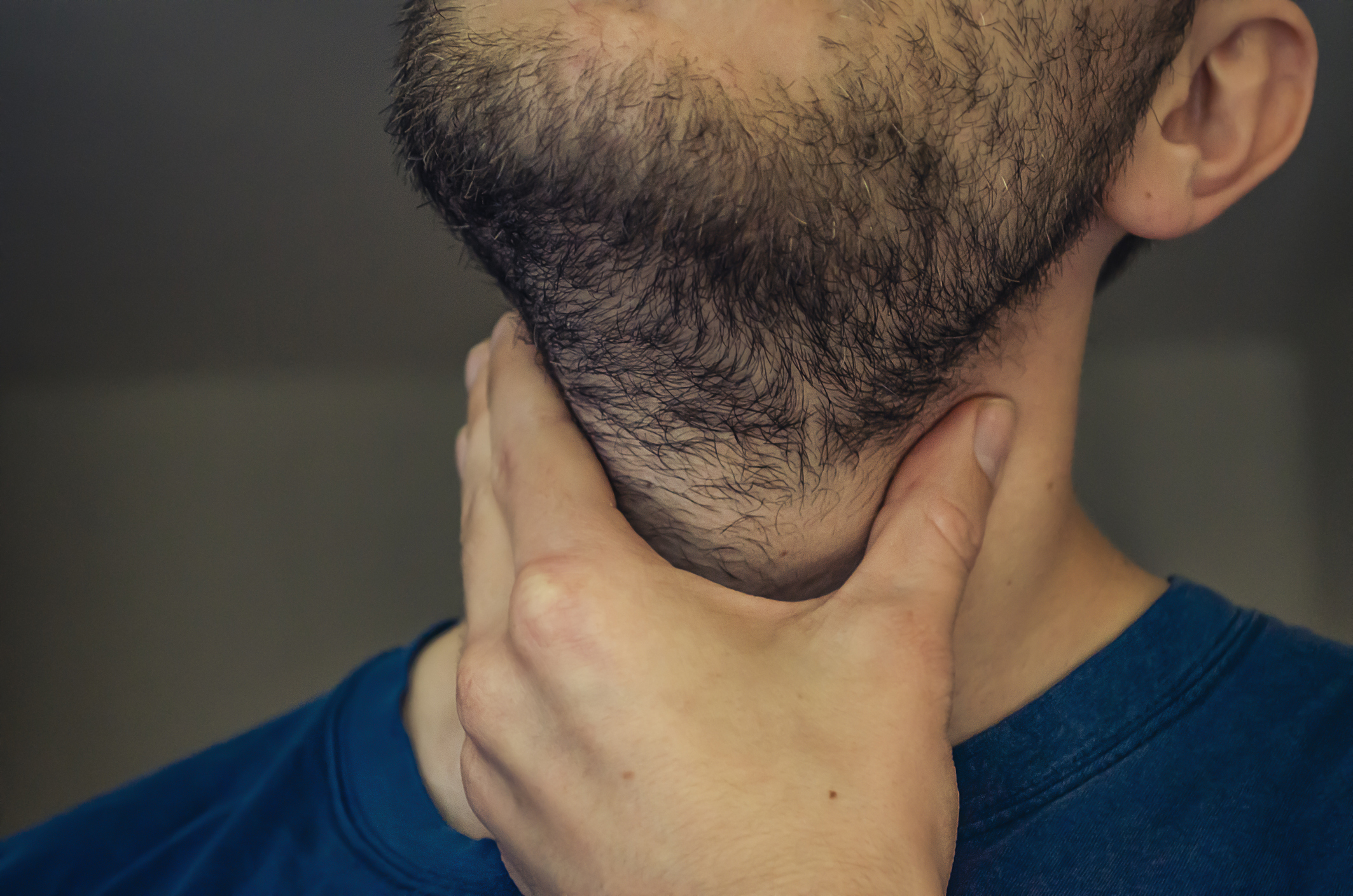 Close-up of a person holding the back of their neck, emotions or discomfort possibly implied