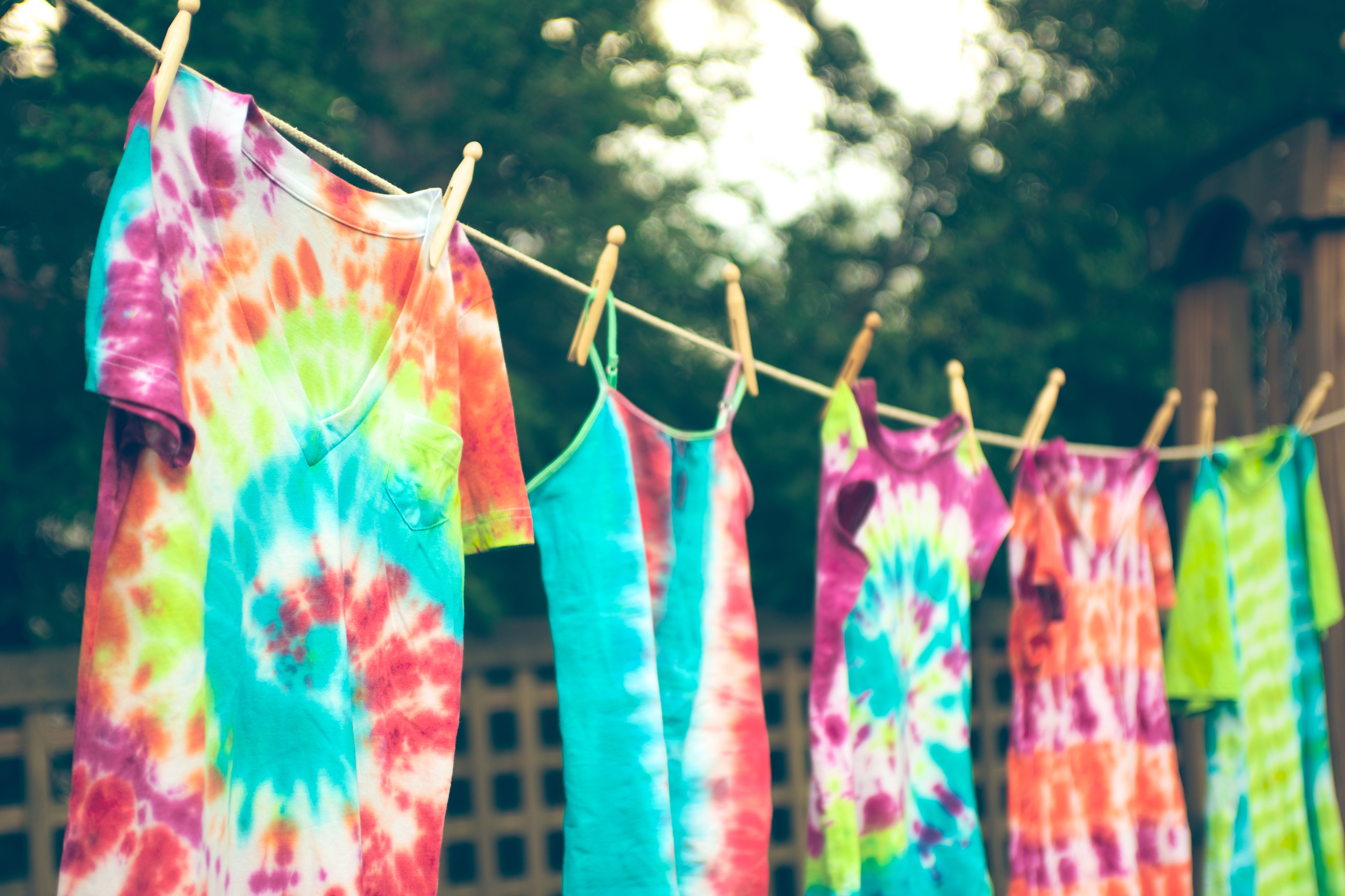 Five tie-dye shirts hanging on a line, indicative of past fashion trends