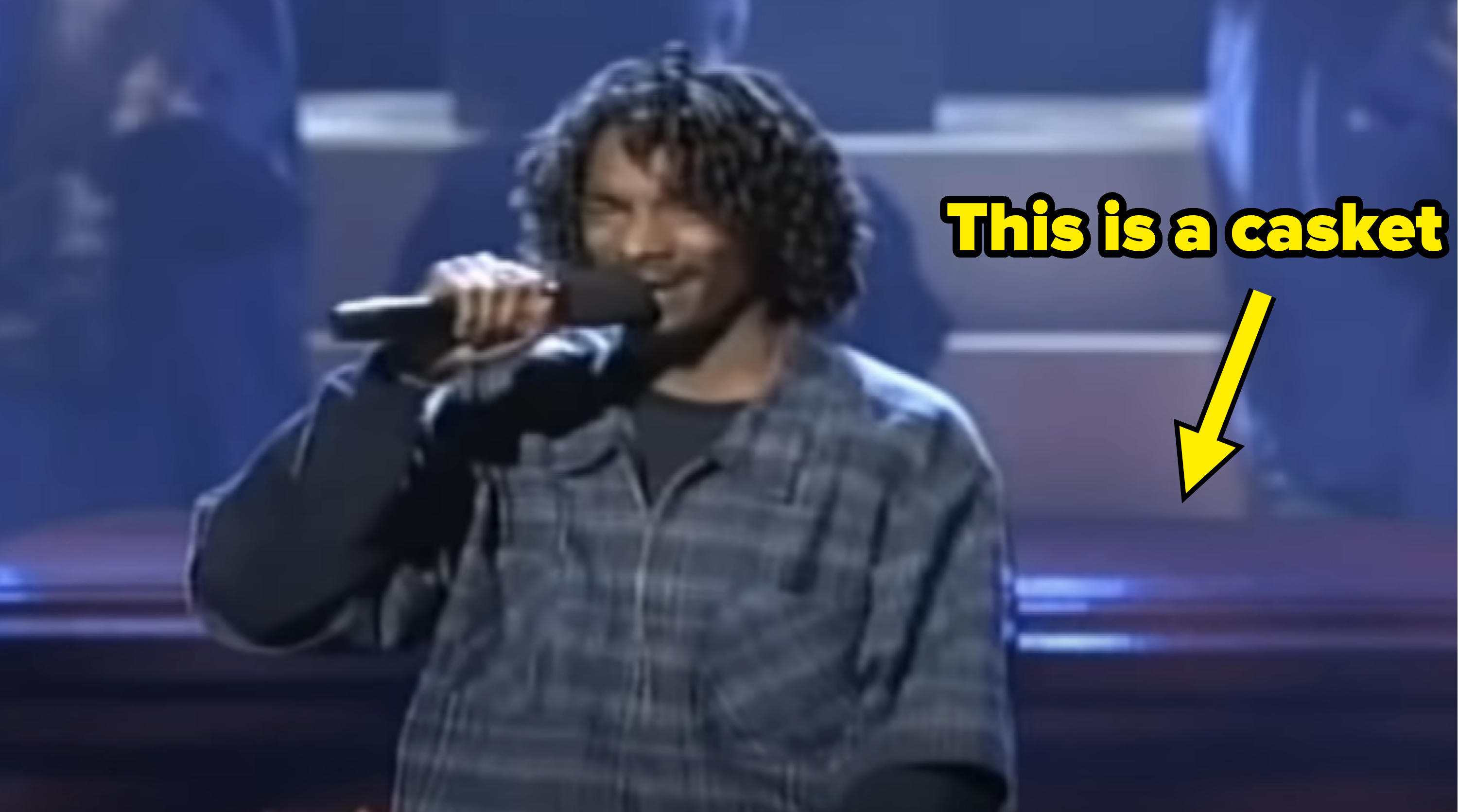 Snoop in a plaid shirt performing on stage with a microphone