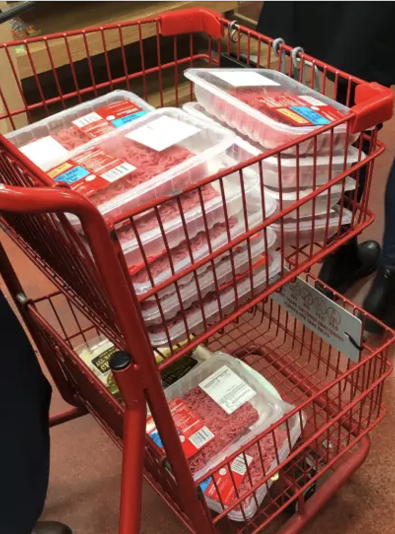 A shopping cart filled with packages of raw meat