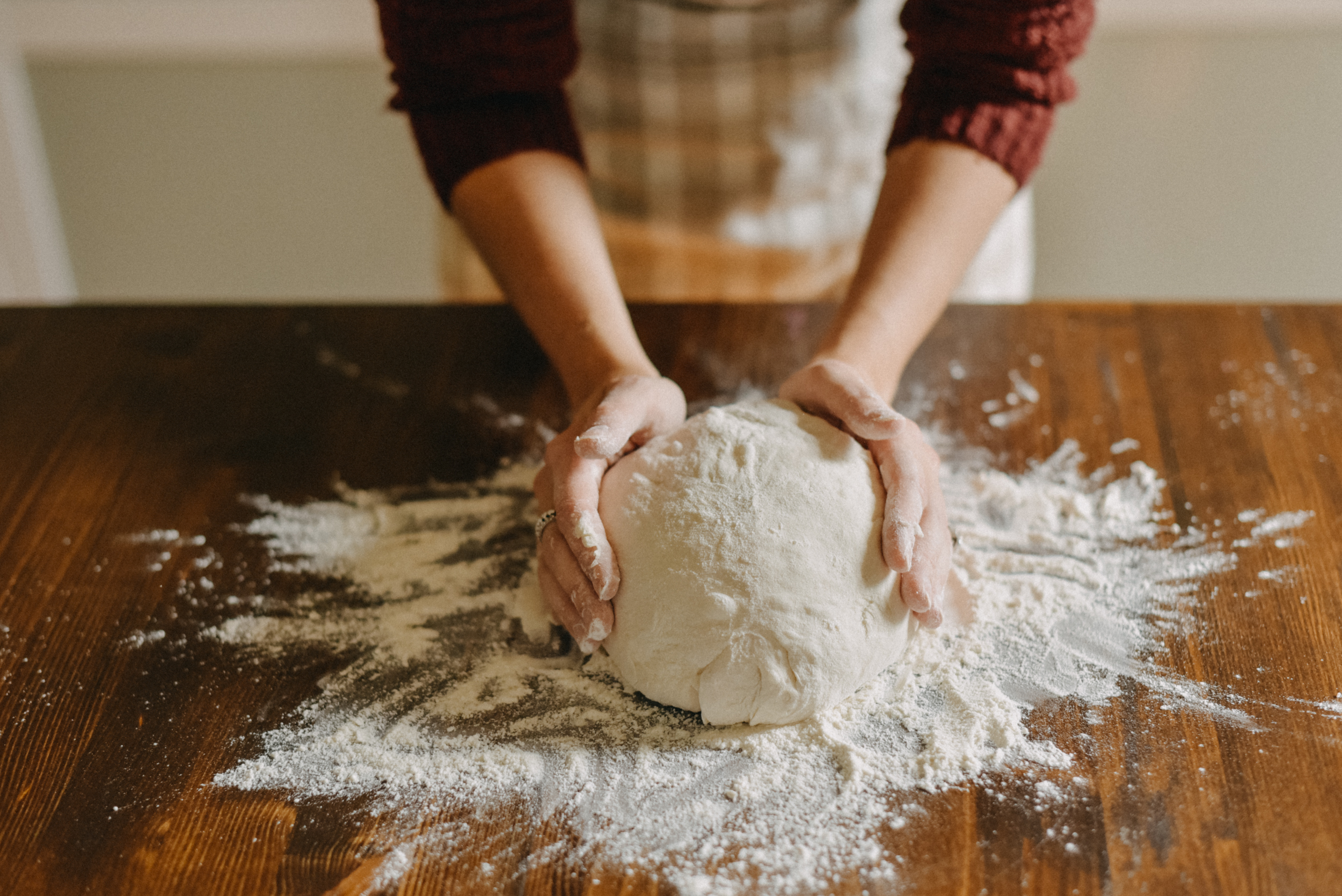 Person kneading dough on a wooden surface