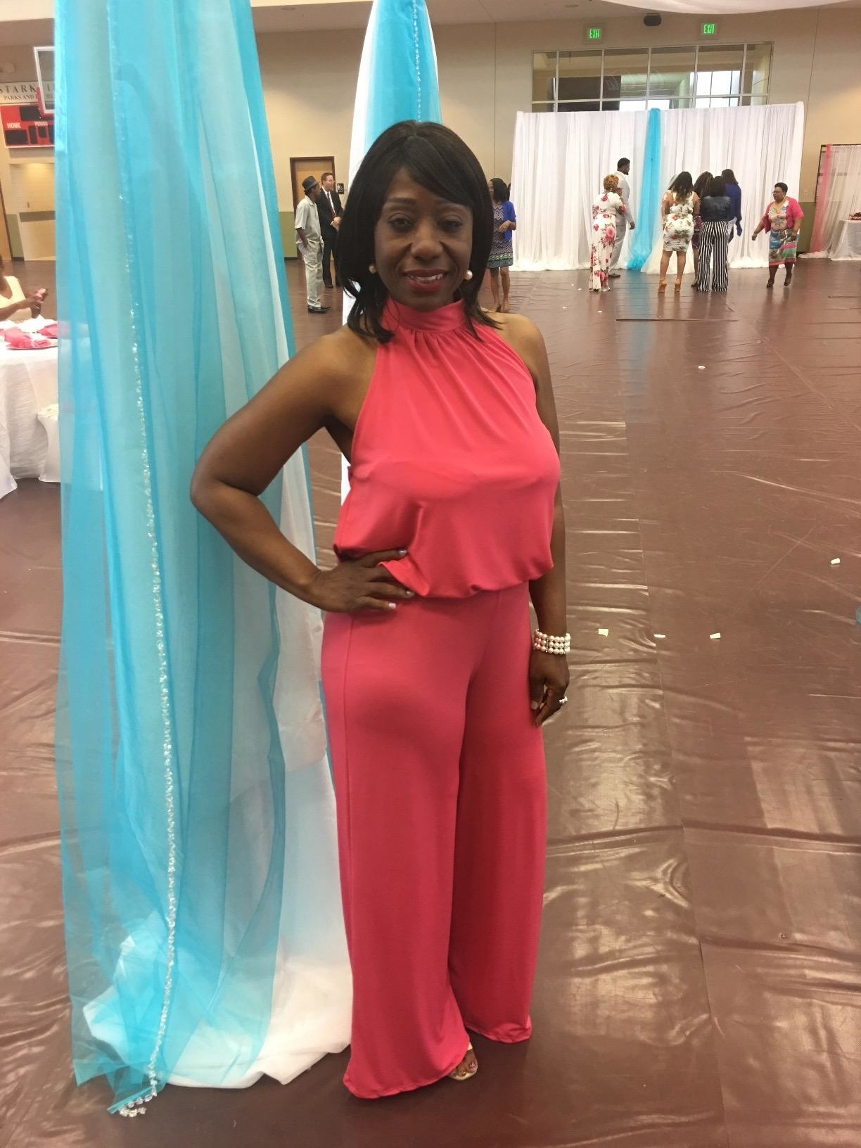 reviewer posing in pink halter jumpsuit inside at event