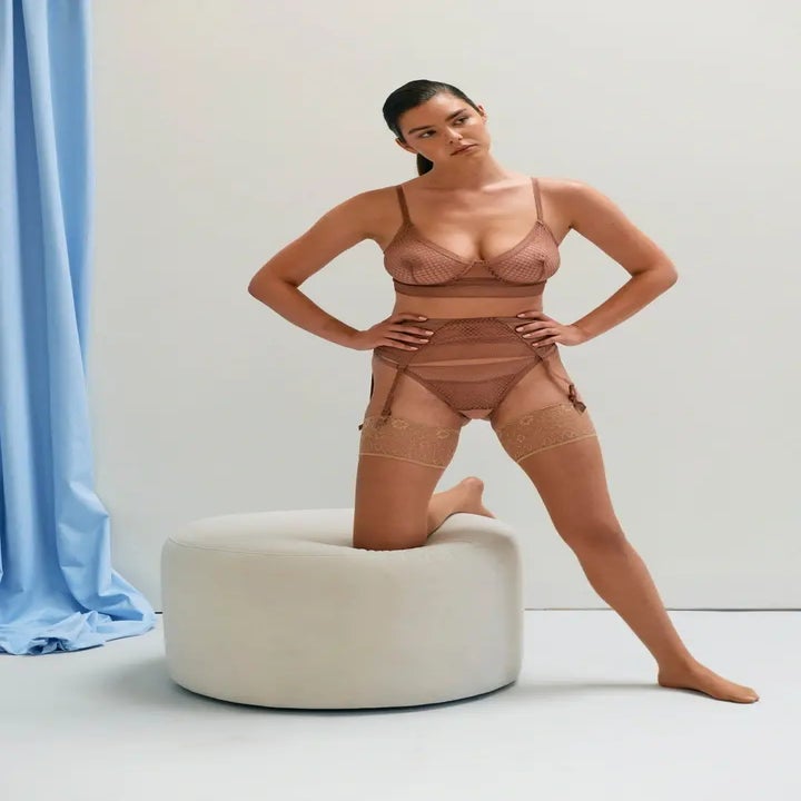 A model poses in a lingerie set with bra, panties, and garters