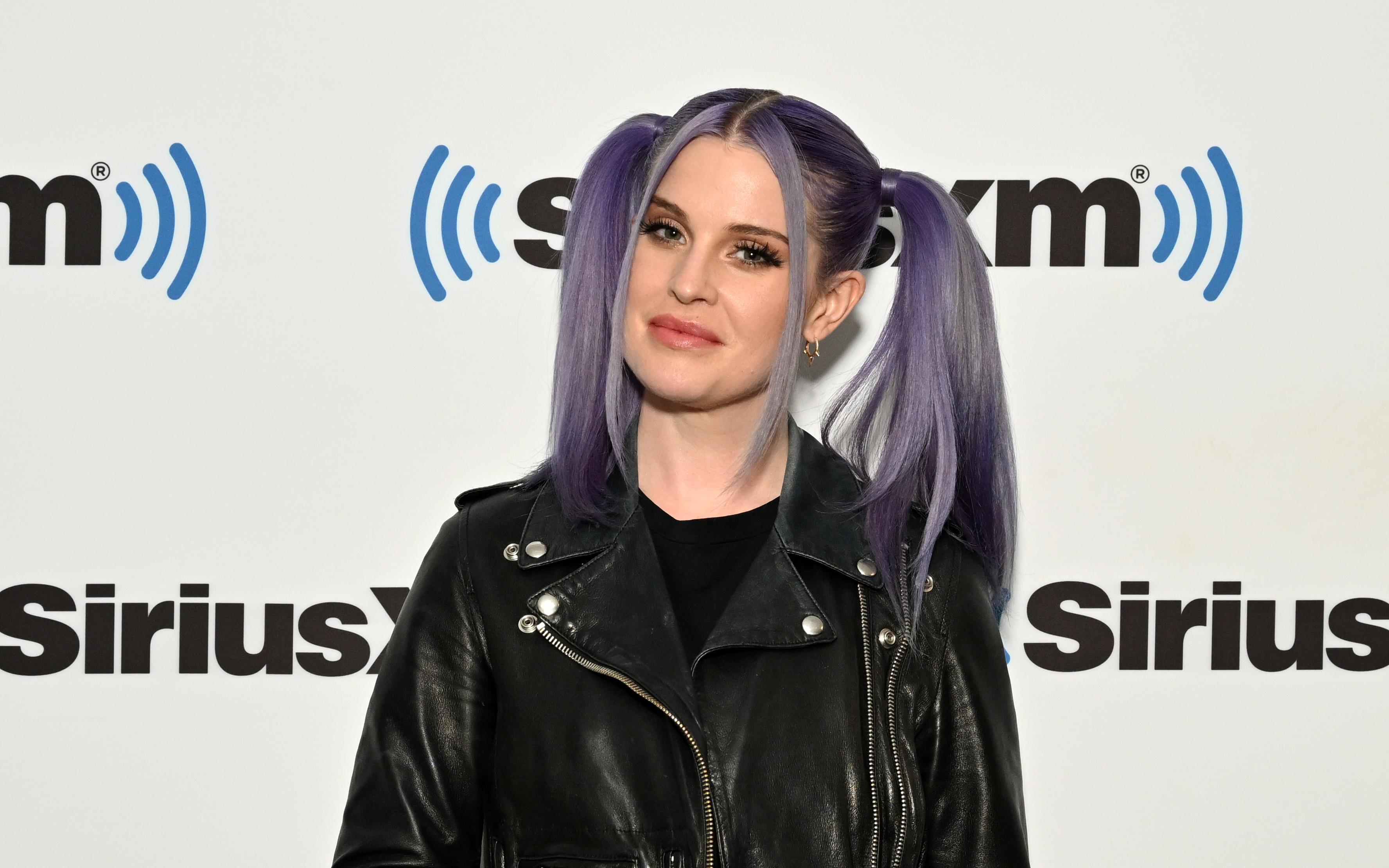 Kelly Osbourne posing in a leather jacket at a SiriusXM event