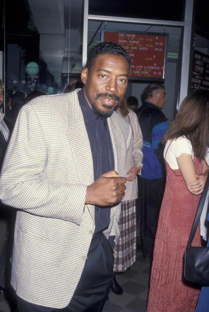 Ernie Hudson in a checkered jacket, and dark shirt, posing for the camera on a premiere night