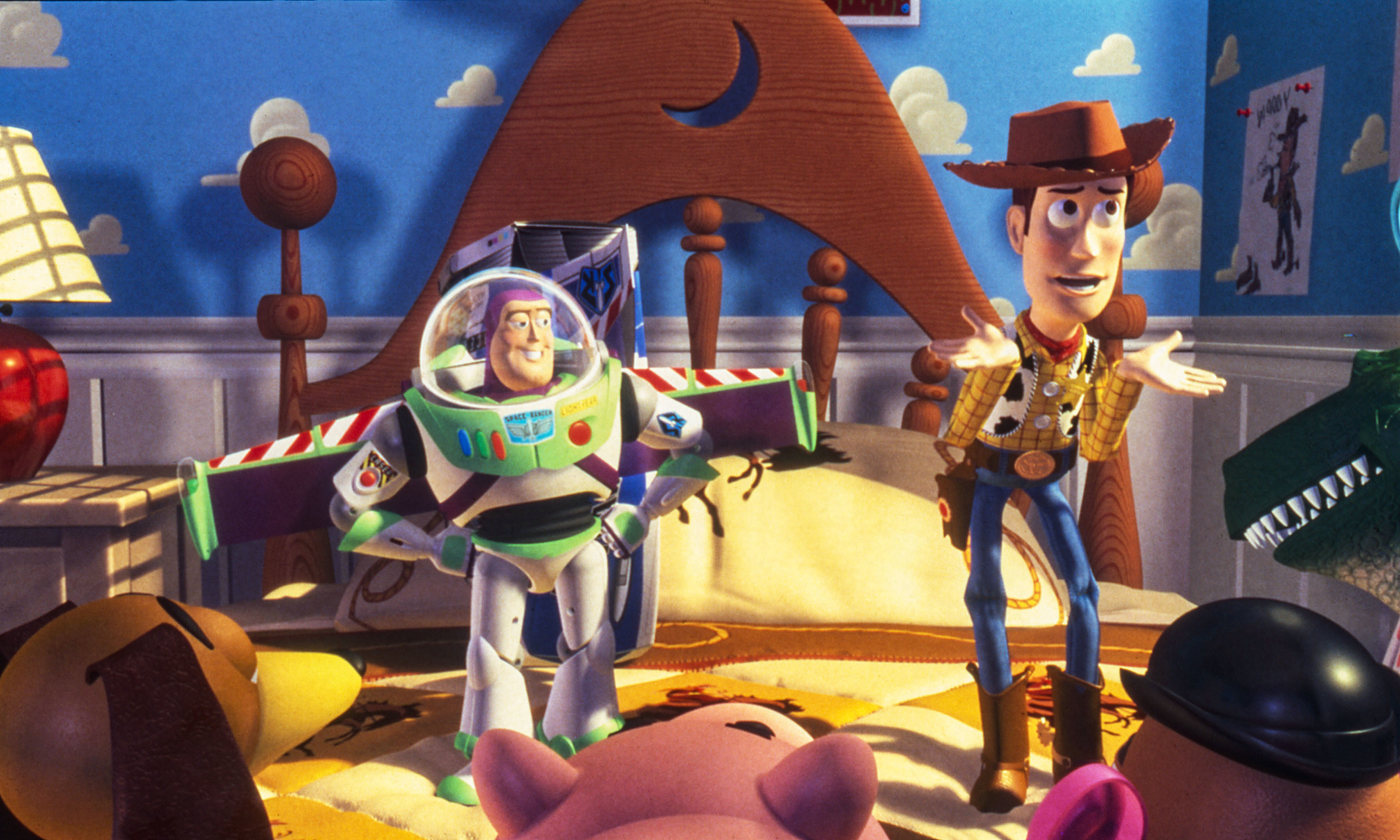 Buzz Lightyear and Woody from Toy Story stand in a cartoon room with toys. Buzz is wearing a space suit; Woody is in a cowboy outfit
