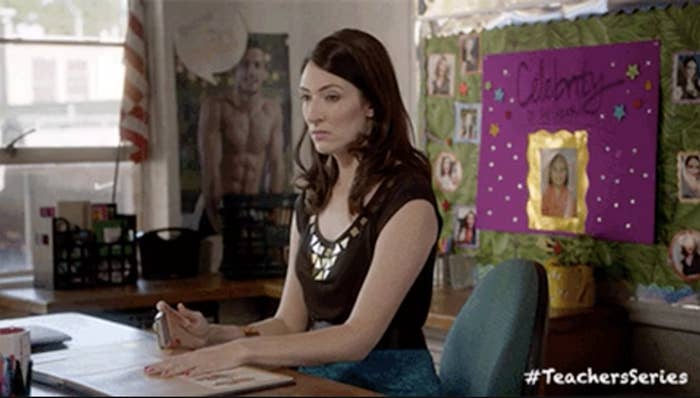 Woman seated at a desk with posters and a &quot;#TeachersSeries&quot; hashtag on the wall