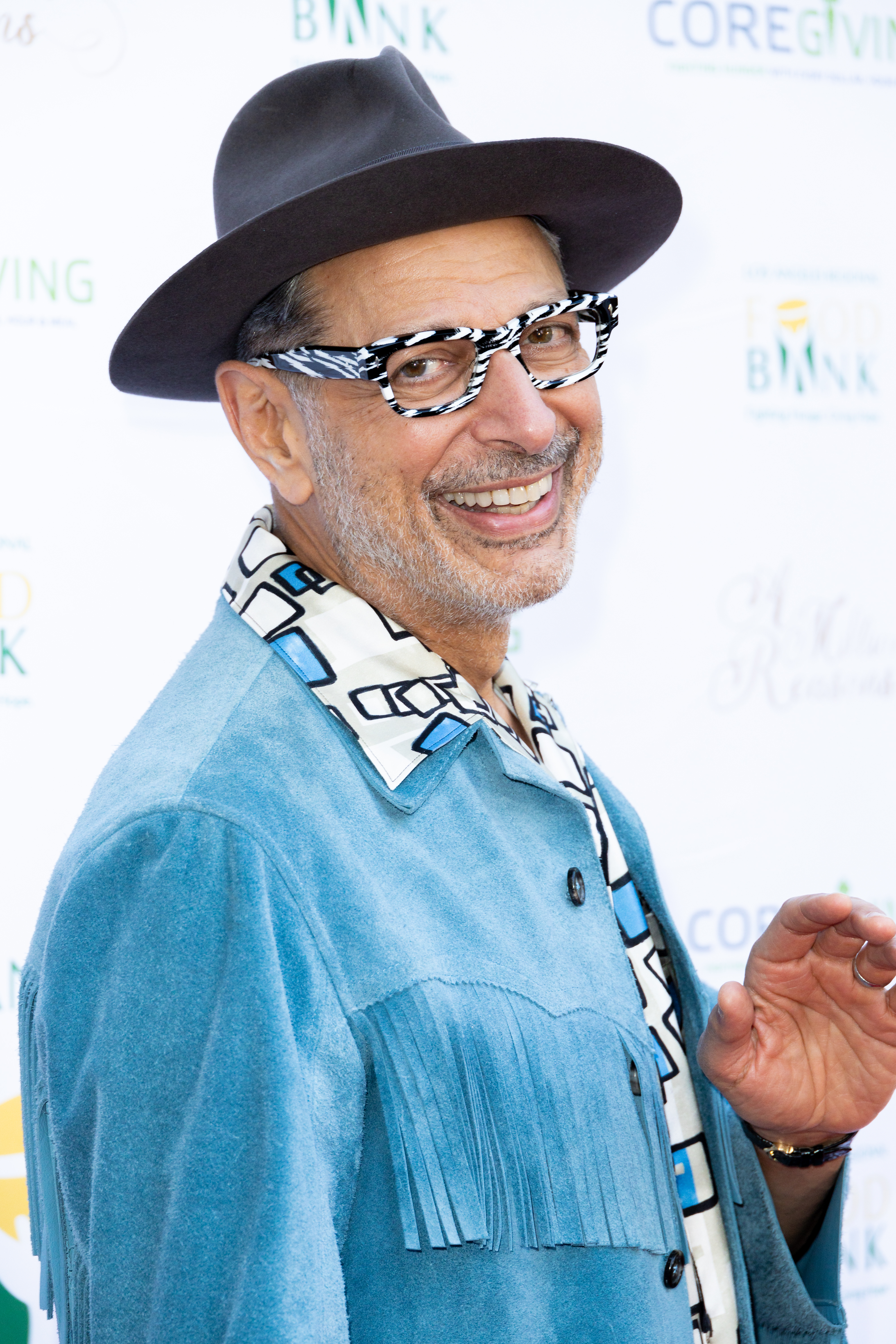 Man in a wide-brimmed hat and patterned shirt, smiling at a charity event