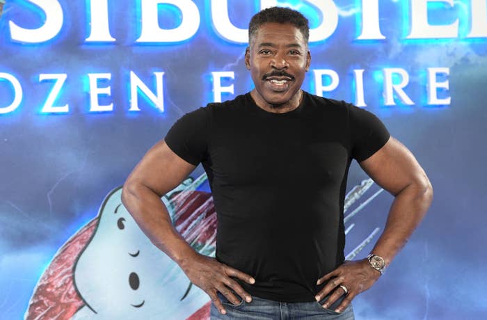 Ernie Hudson wearing a black shirt, posing in front of a &quot;Ghostbusters: Afterlife&quot; backdrop with character art
