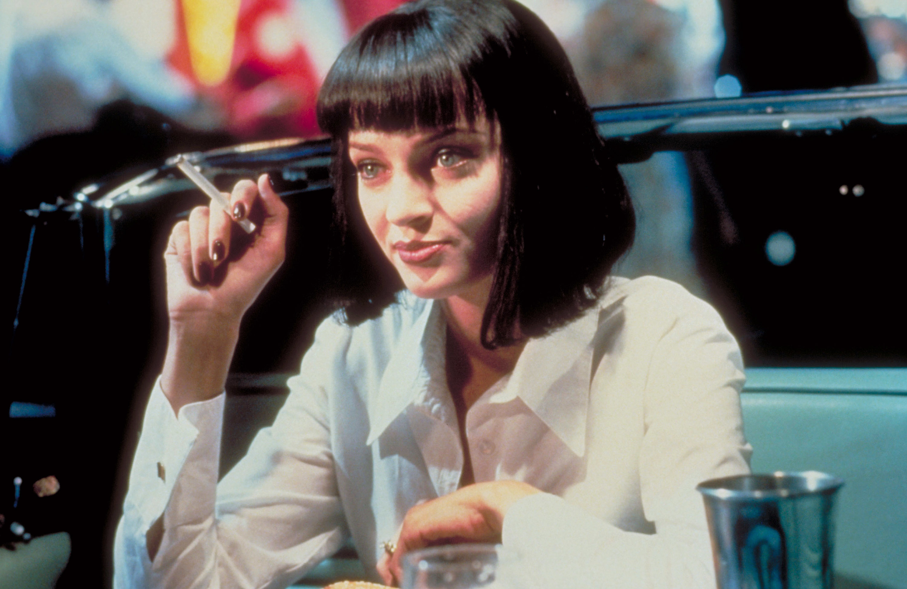 Mia Wallace from Pulp Fiction, seated in a diner booth, with a pen in hand and a bob haircut