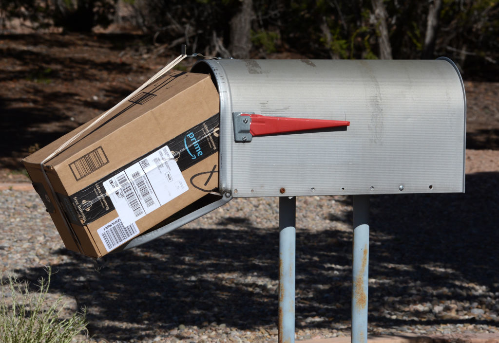 Package protruding from an overstuffed mailbox at a roadside
