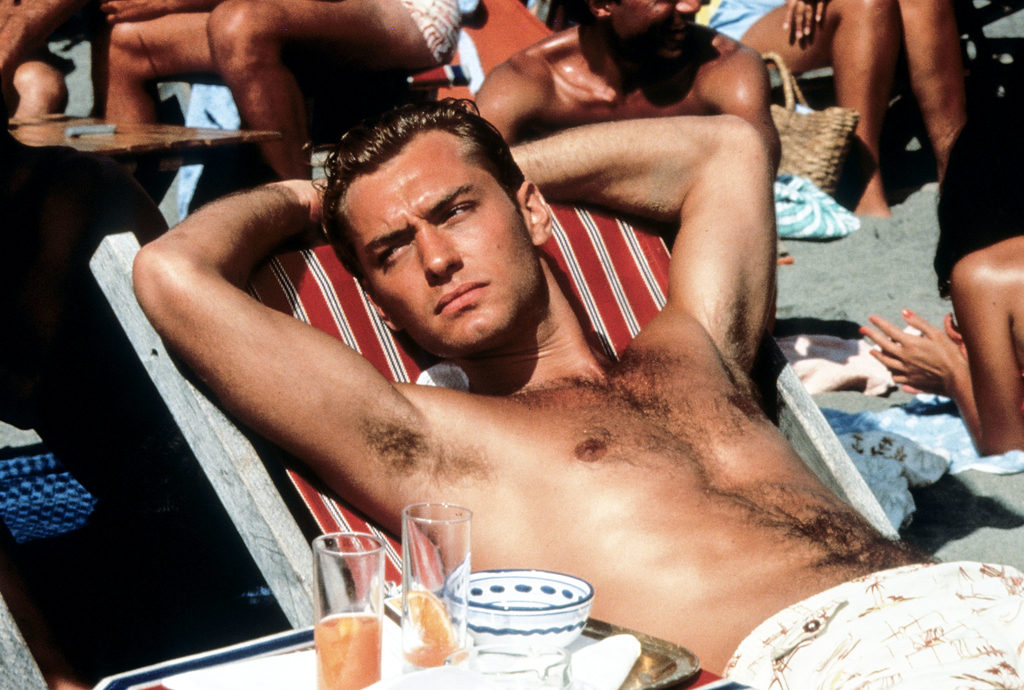 Man reclining on a beach chair surrounded by sunbathers