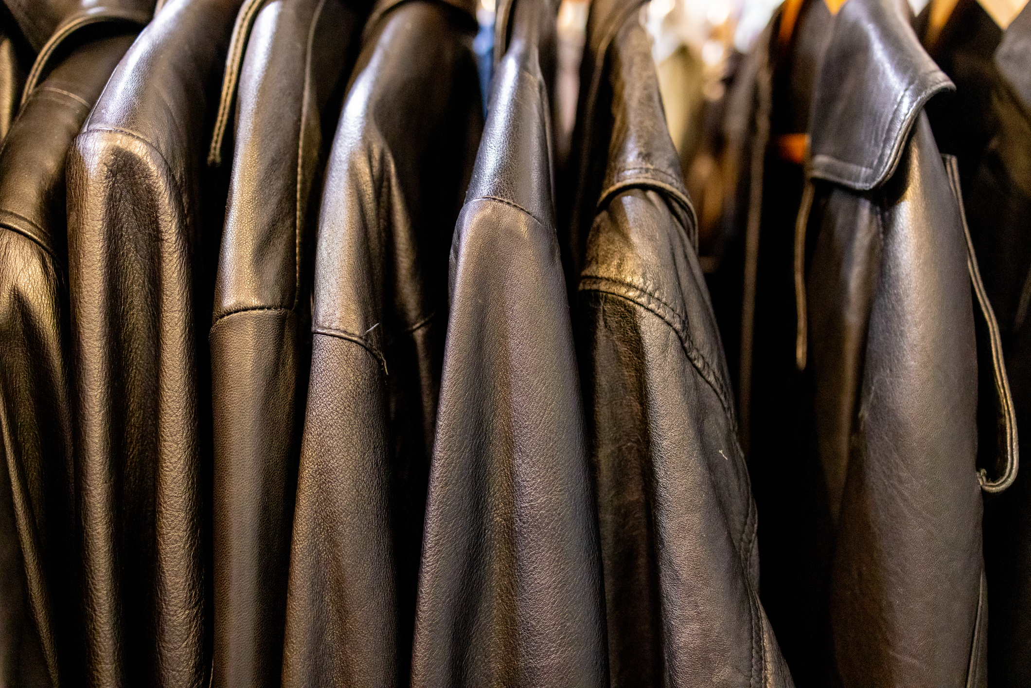 Rack of various styles of leather jackets hanging closely together