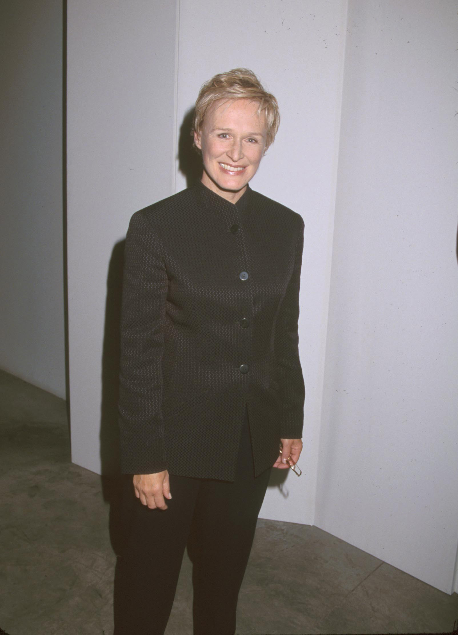 Ellen DeGeneres smiling, wearing a dark patterned suit jacket