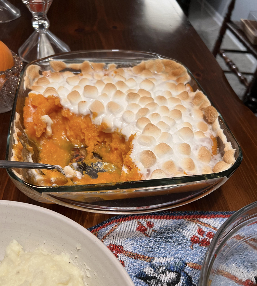 Sweet potato casserole topped with toasted marshmallows, served in a glass dish on a dining table