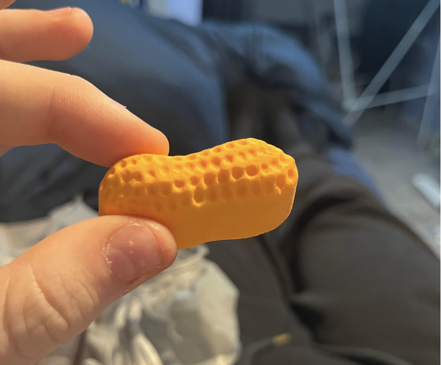 Person holding a peanut-shaped orange puff