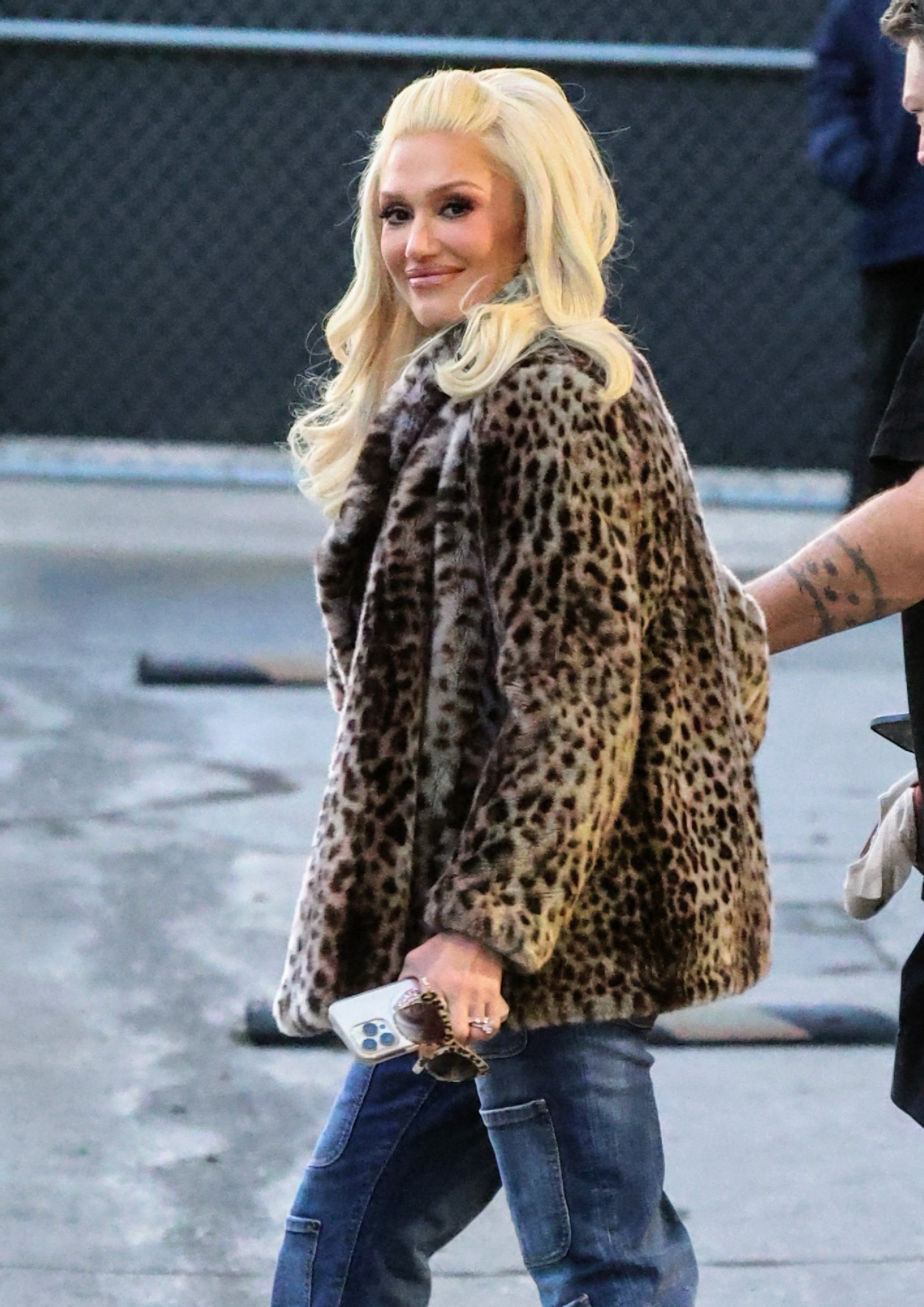 Woman in leopard print coat and jeans looking over her shoulder